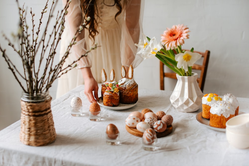 uma mesa coberta com bolos e flores ao lado de um vaso de flores