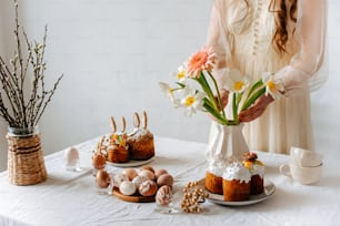 a woman standing next to a table filled with cakes and flowers