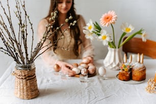 a woman sitting at a table with flowers and eggs