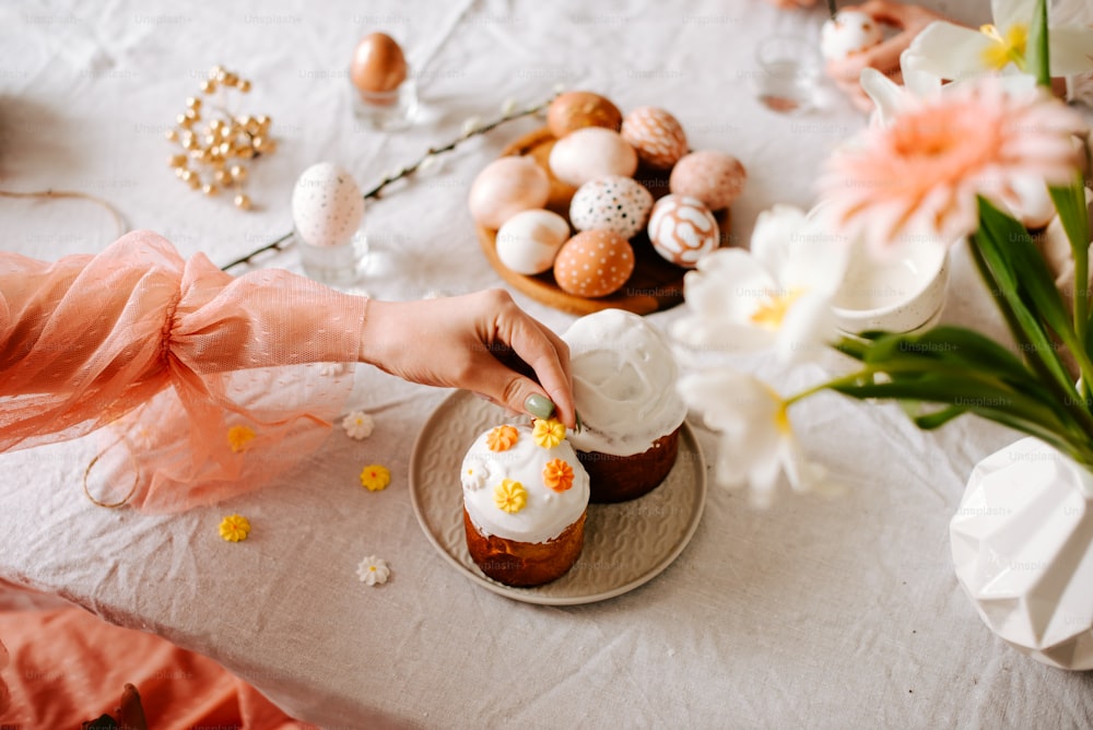 a woman is decorating a cupcake with white frosting