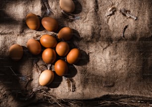 a bunch of brown eggs laying on top of a cloth