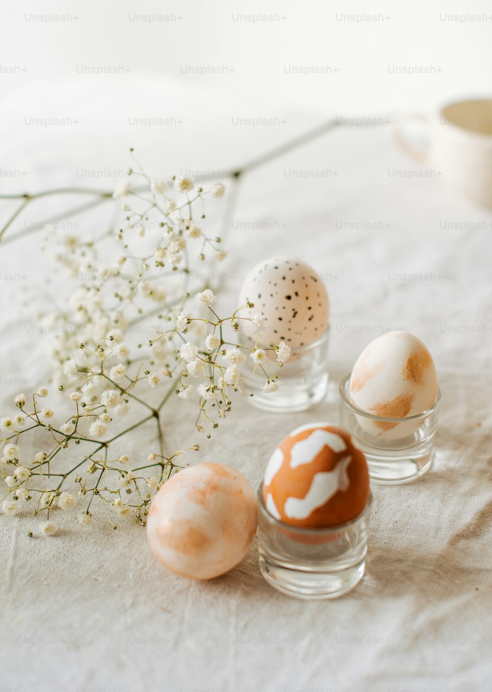 테이블에 페인트 칠한 계란으로 채워진 세 개의 유리 꽃병
