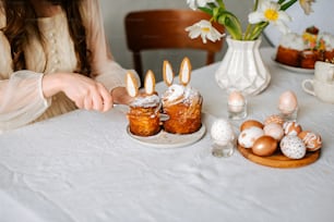 Una mujer está decorando unos pasteles con orejas de conejo