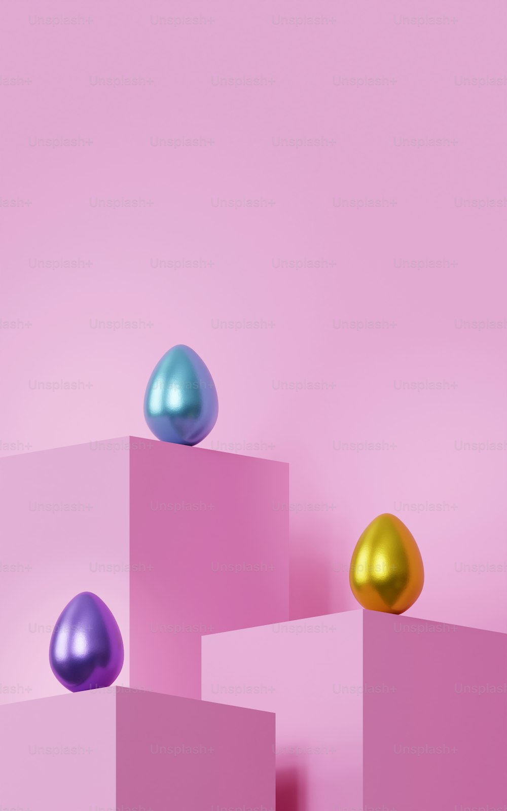 three metallic eggs on top of pink blocks