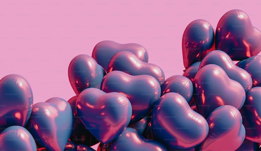 um monte de balões em forma de coração contra um fundo rosa