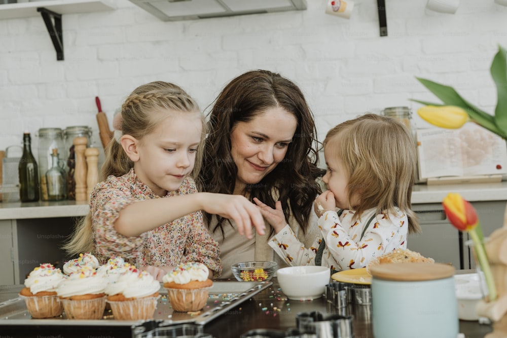 a woman and two little girls standing in front of cupcakes