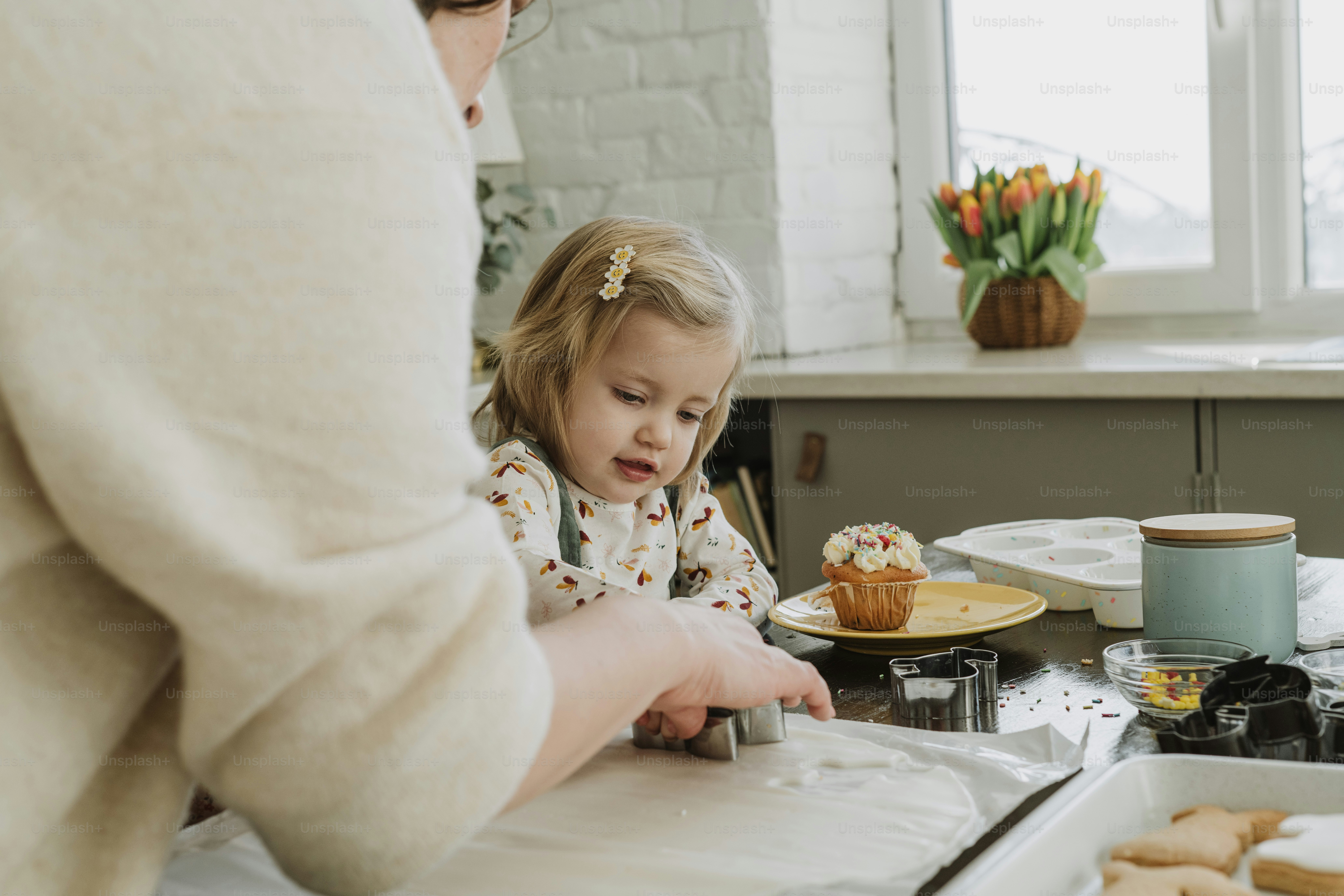 컵케이크 앞 테이블에 앉아 있는 어린 소녀