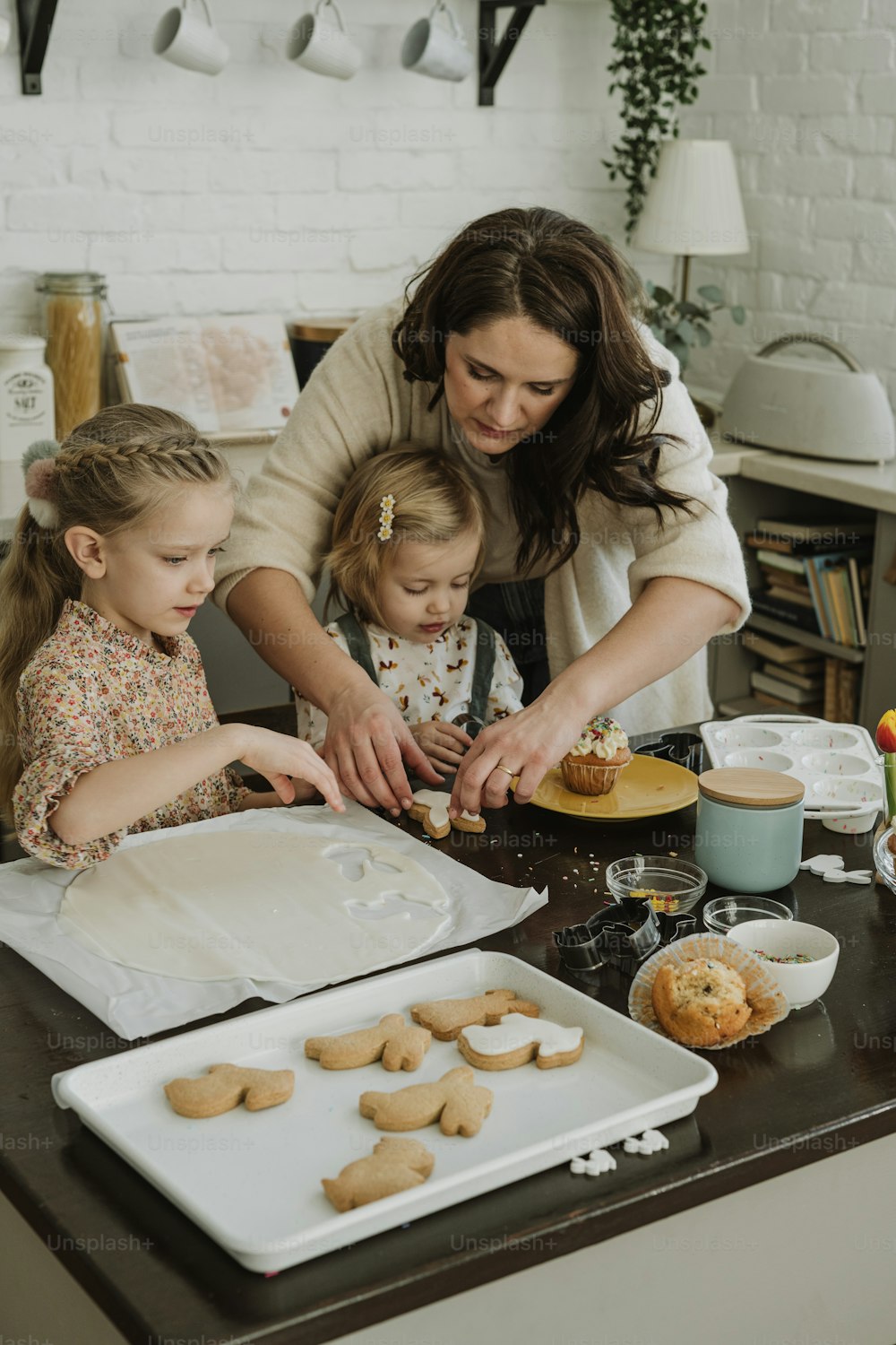a woman and two young girls making cookies