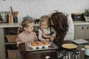a woman and two little girls standing in front of a tray of cupcakes