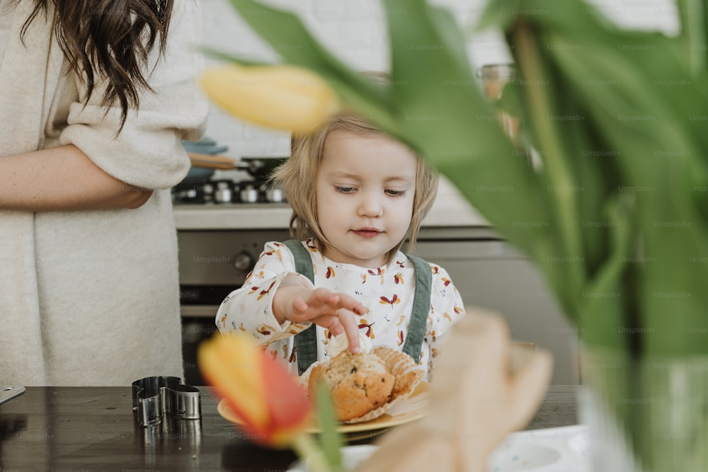 Una niña sentada en una mesa con un plato de comida