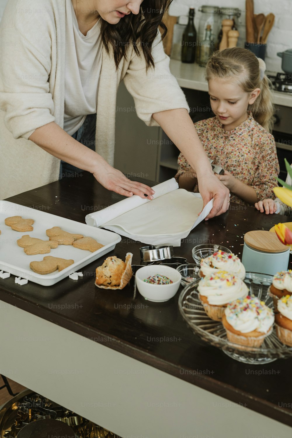 a woman and a little girl making cupcakes