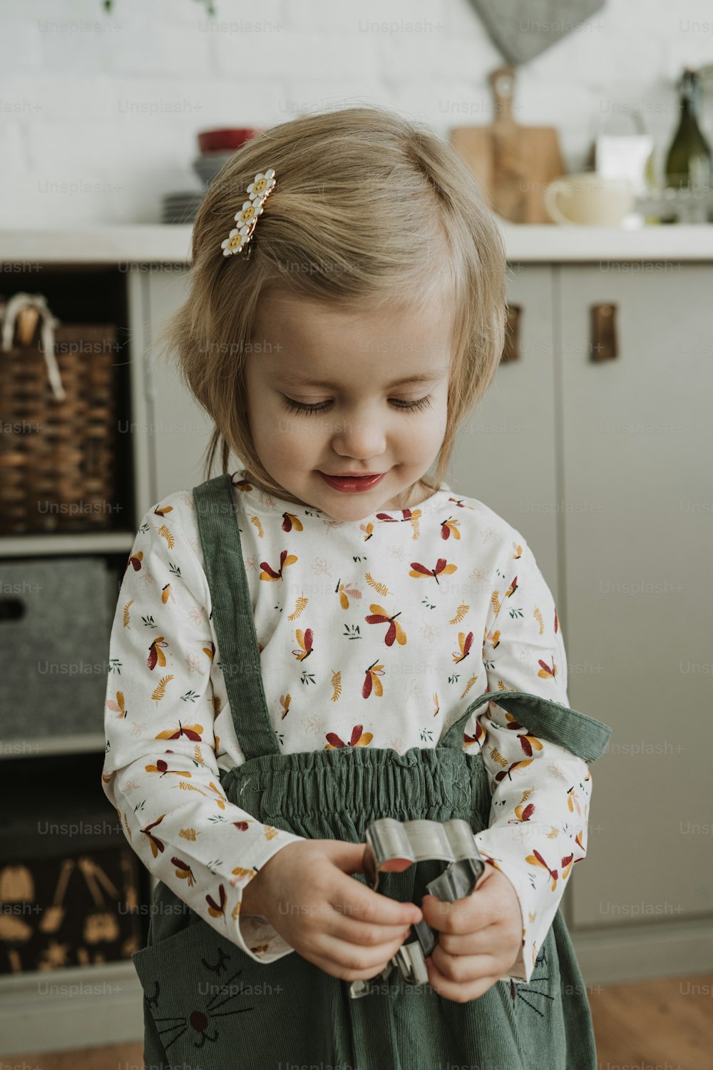 a little girl standing in a kitchen holding a pair of scissors