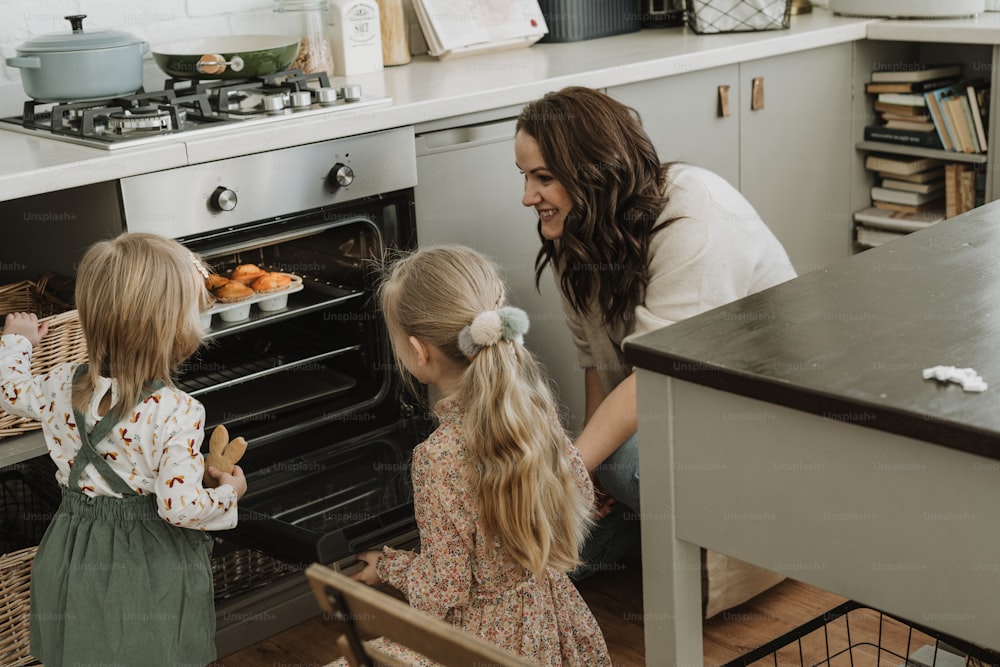 a woman and two little girls looking into an oven