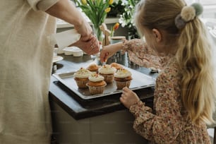 a little girl reaching for a cupcake on a tray
