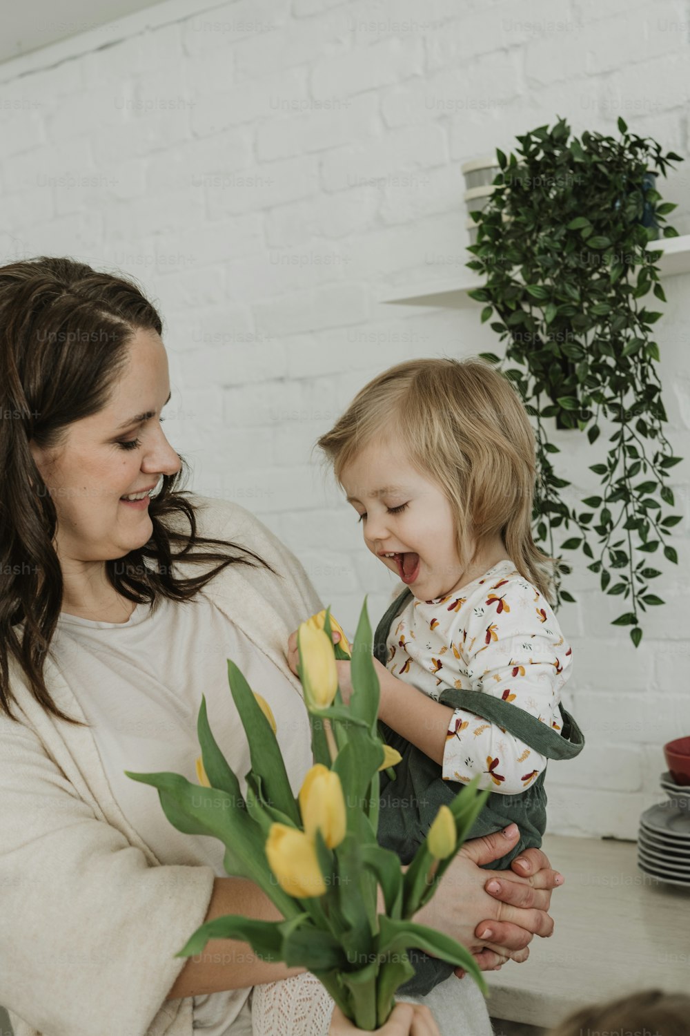 a woman holding a child and a vase of flowers