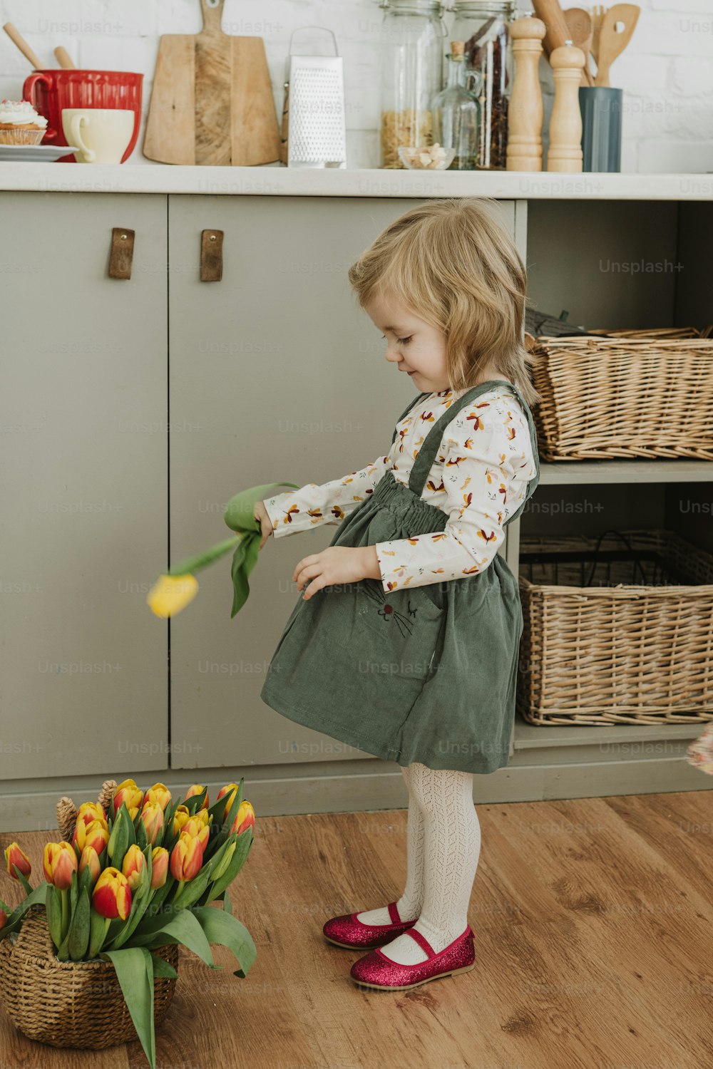 a little girl holding a bunch of tulips in a kitchen
