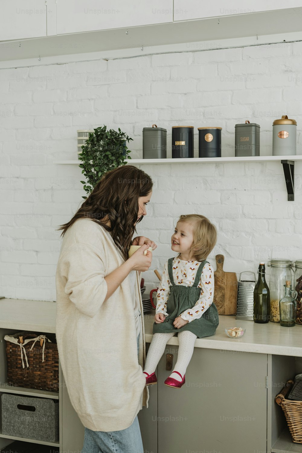 a woman standing next to a little girl in a kitchen