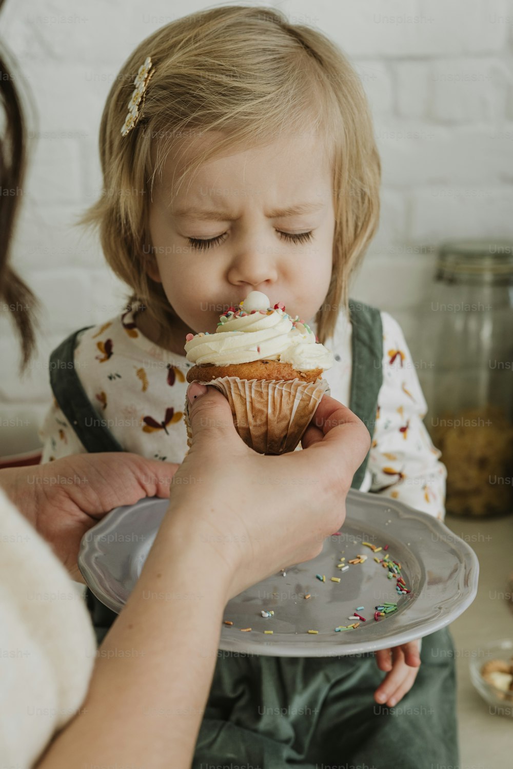 a little girl is eating a cupcake on a plate