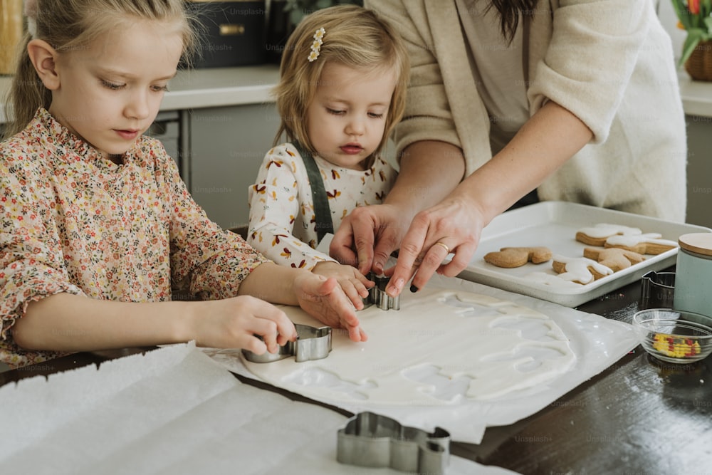 a woman and two children are making cookies