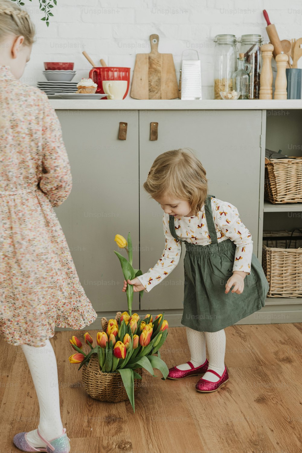 a little girl standing next to a basket filled with tulips