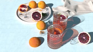 a table topped with two glasses filled with blood oranges