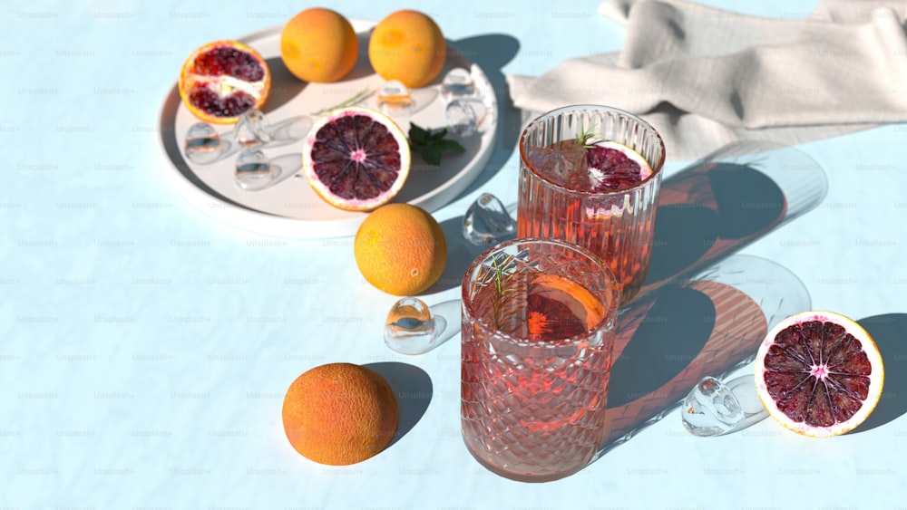 a table topped with two glasses filled with blood oranges