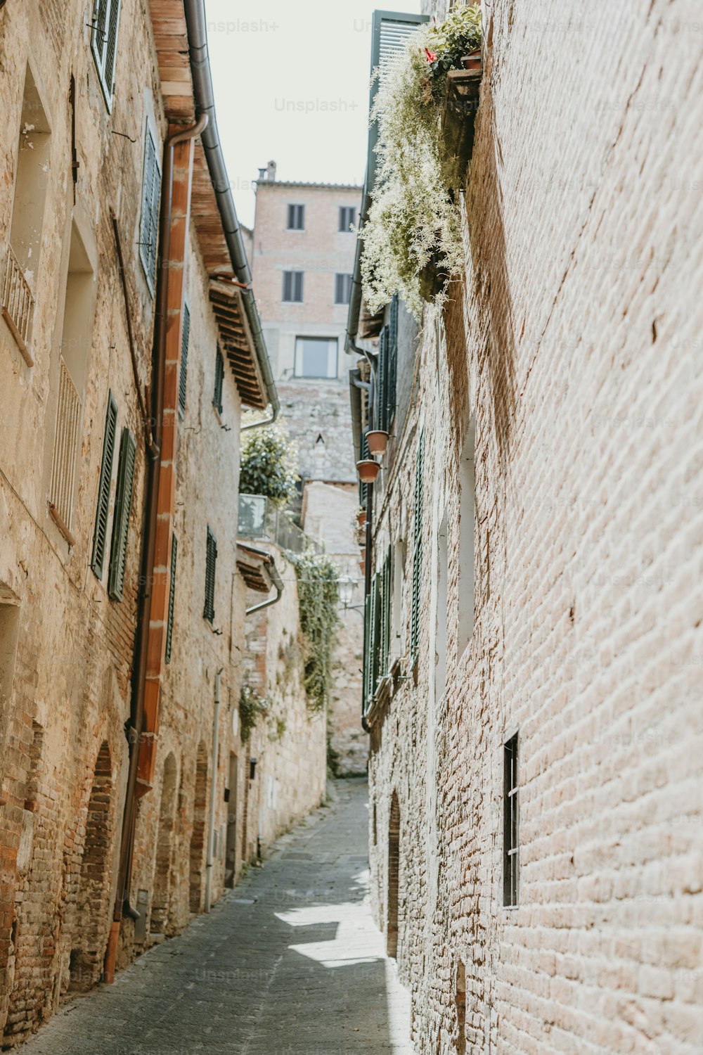 a narrow alley way with brick buildings and green shutters