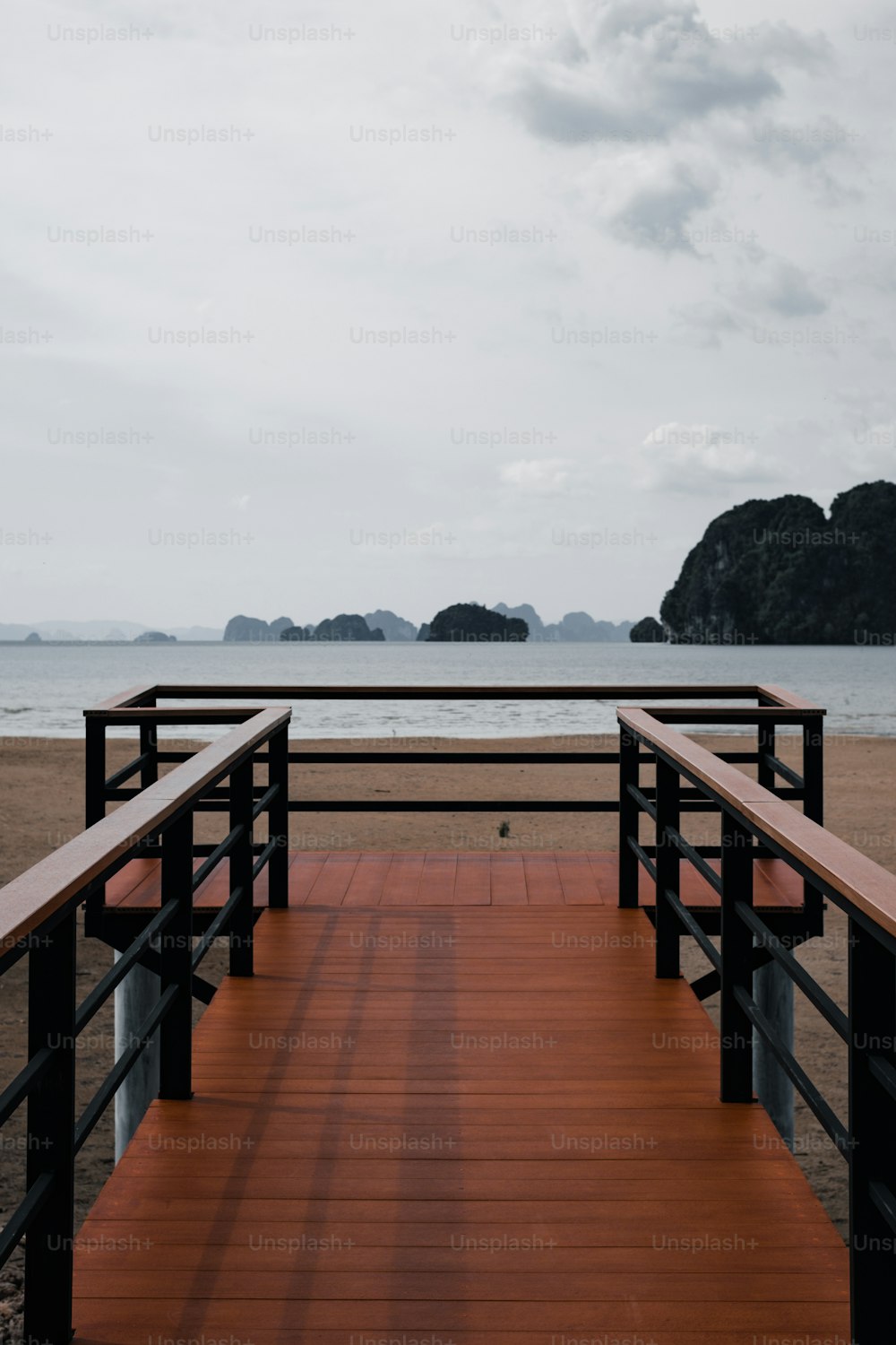 a wooden walkway leading to a beach with mountains in the background