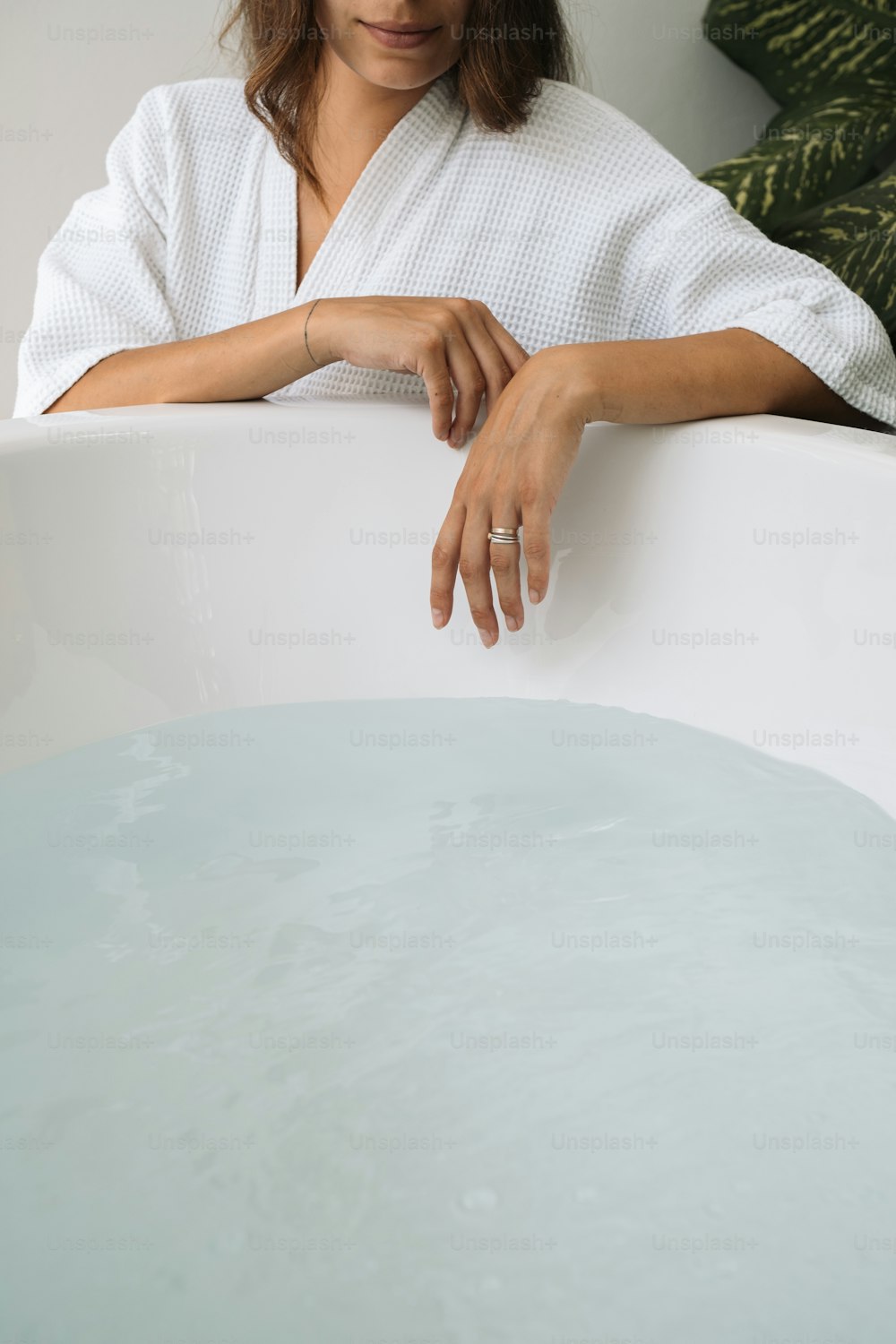 a woman in a bathrobe leaning on a bath tub