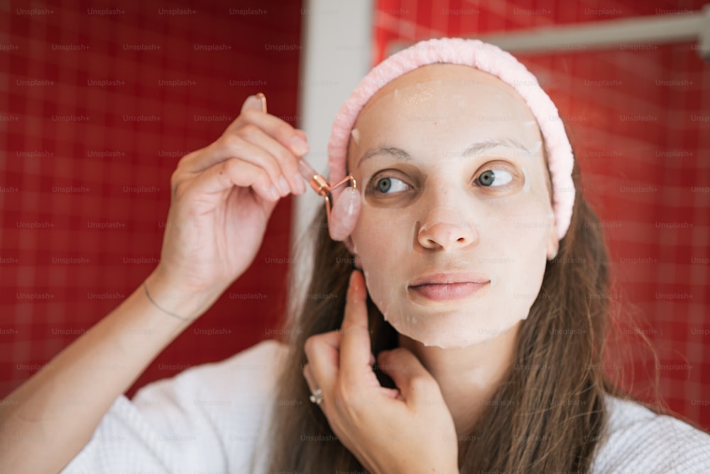 a woman with a pink headband is putting makeup on her face