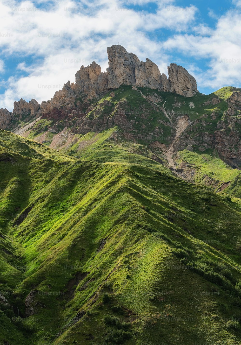 a mountain range with green grass on the side of it