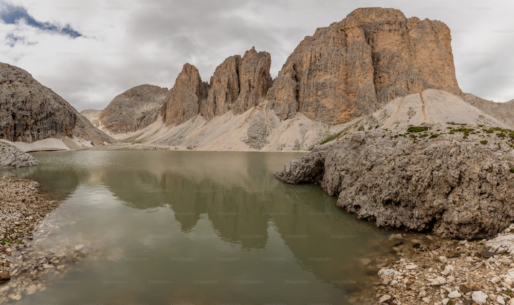 a body of water surrounded by mountains under a cloudy sky