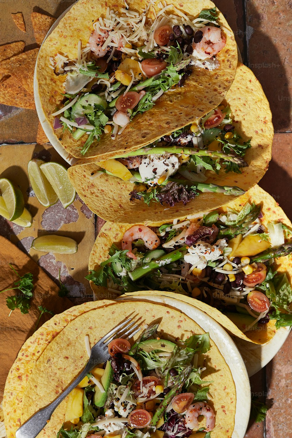a table topped with three tacos filled with veggies