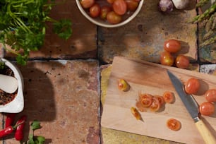 une planche à découper avec des tomates dessus à côté d’une plante en pot