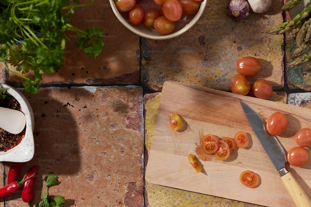 una tabla de cortar con tomates junto a una planta en maceta