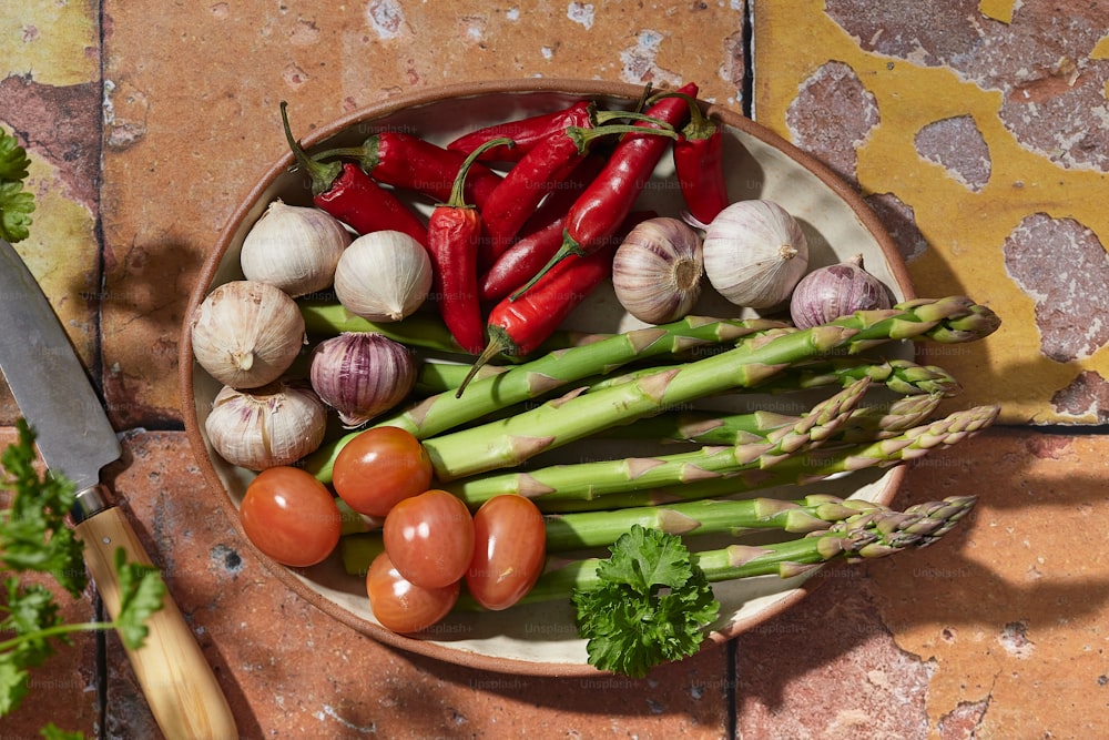 eine Schüssel Gemüse und ein Messer auf einem Tisch