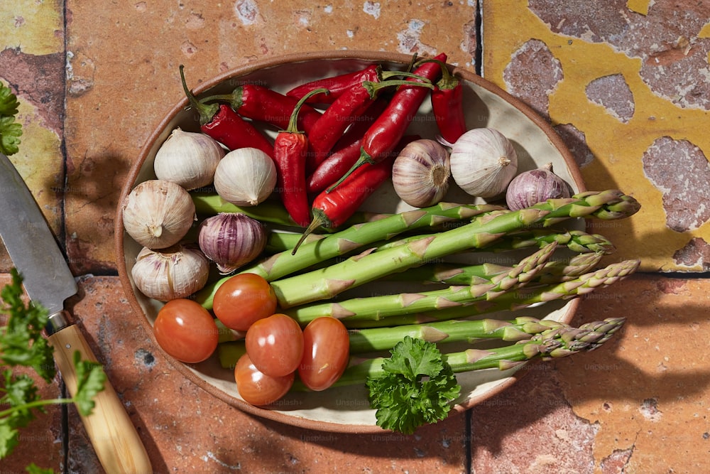 a bowl of vegetables and a knife on a table