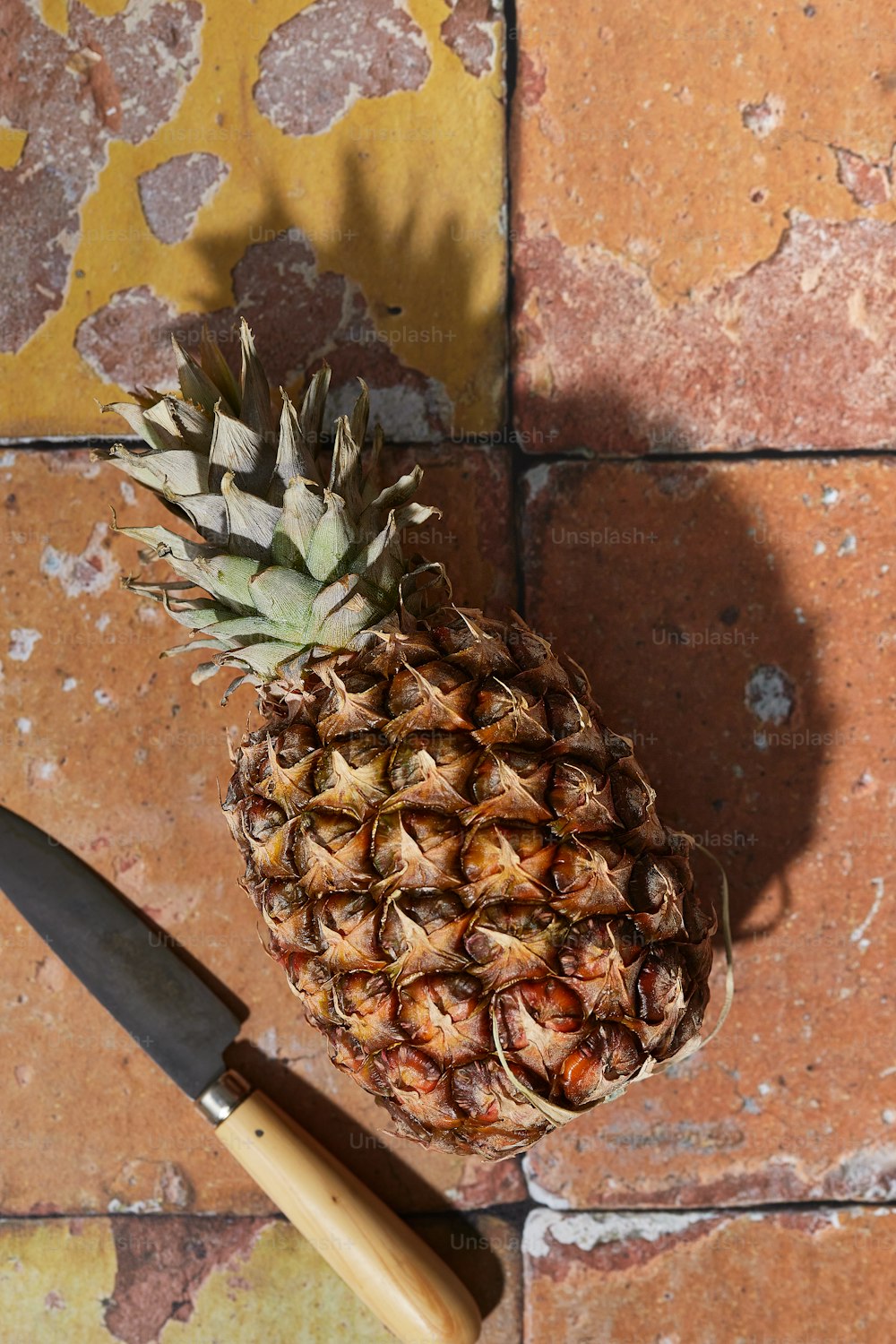um abacaxi sentado em cima de uma mesa ao lado de uma faca