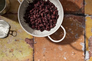 a colander filled with beans sitting on a tiled floor