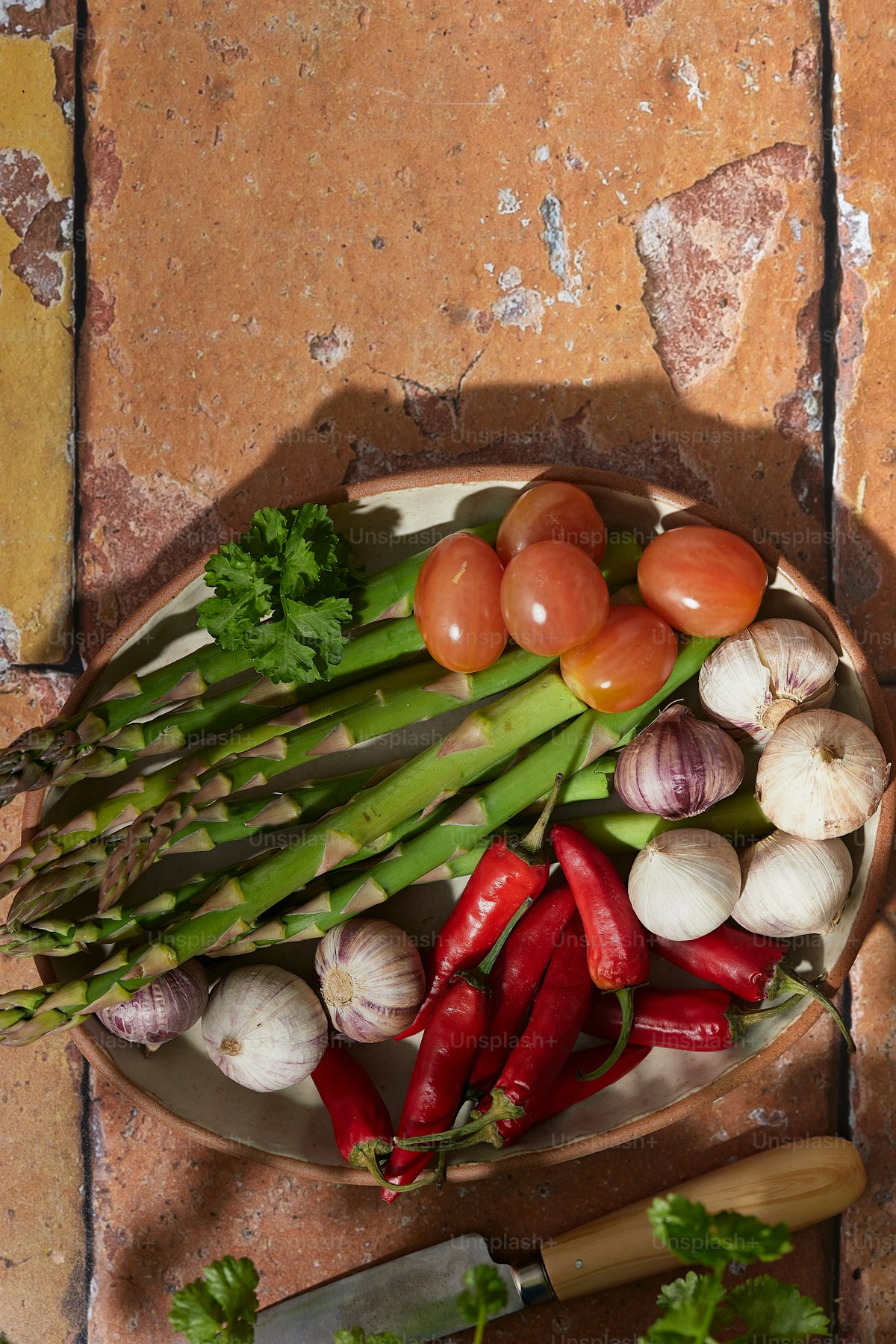 Plate of vegetables and a knife on a wooden table, whole-foods still life
