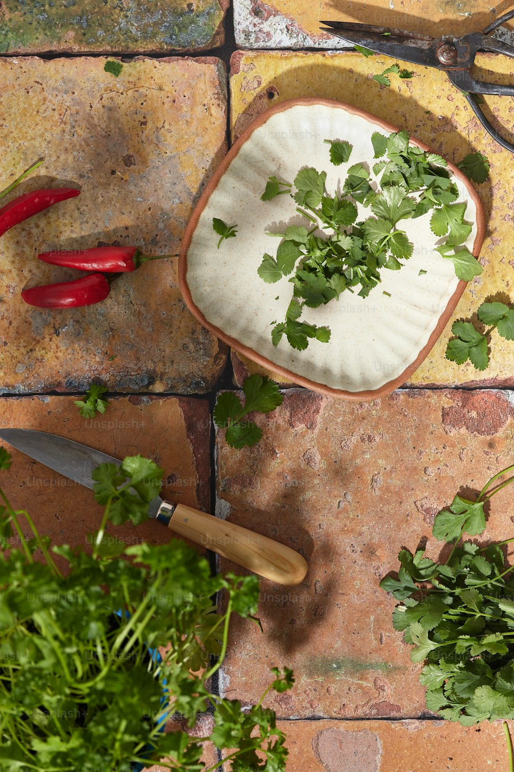 una tabla de cortar cubierta con hojas verdes junto a un cuchillo