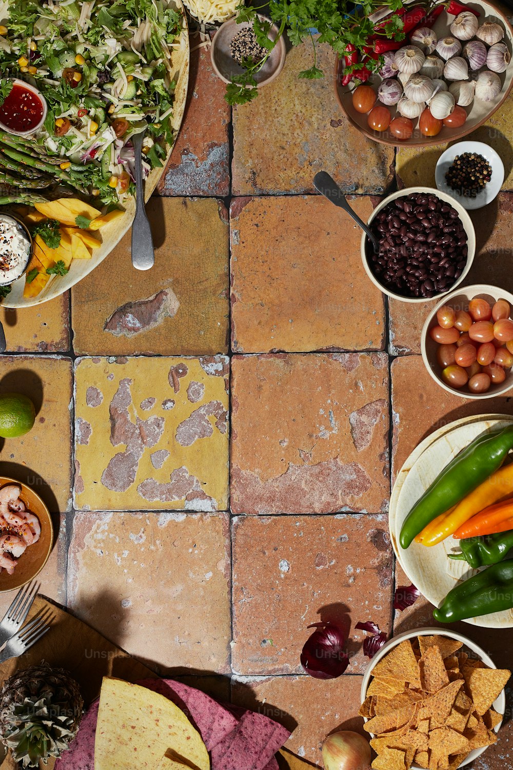 une table remplie de bols de nourriture sur un sol carrelé