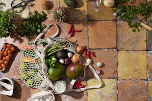 a variety of fruits and vegetables sitting on a tiled floor