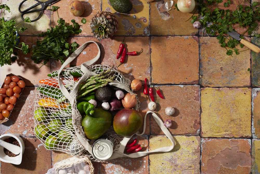 a variety of fruits and vegetables sitting on a tiled floor