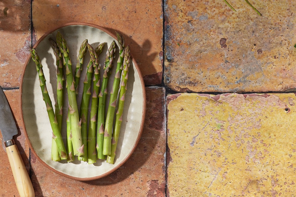 a plate of asparagus and a knife on a table