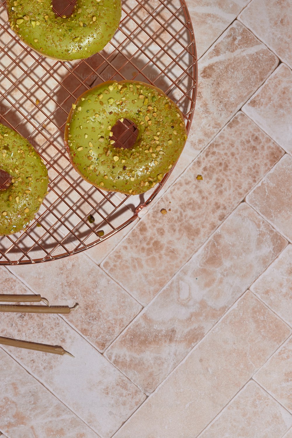 three donuts with green toppings on a wire rack