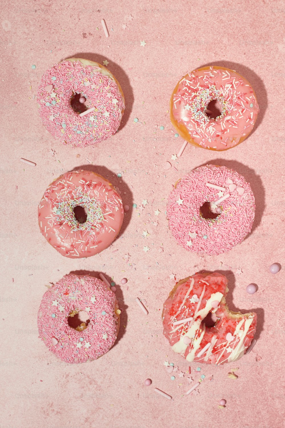 four donuts with pink frosting and sprinkles
