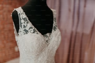 a wedding dress on a mannequin in front of a brick wall