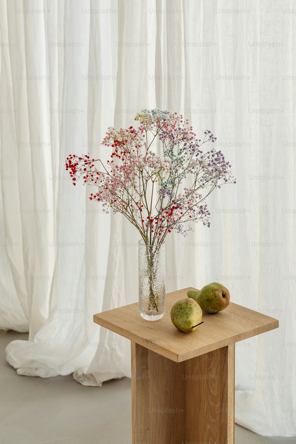 eine Vase mit Blumen und Obst auf einem Tisch