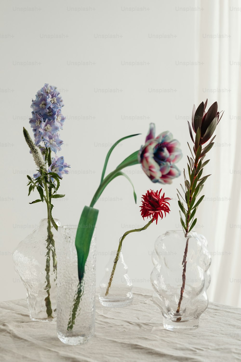 Tres jarrones de vidrio con flores en ellos sobre una mesa